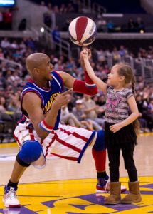 Scooter Christensen helps a child learn how to spin a basketball. / Courtesy of Harlem Globetrotters 